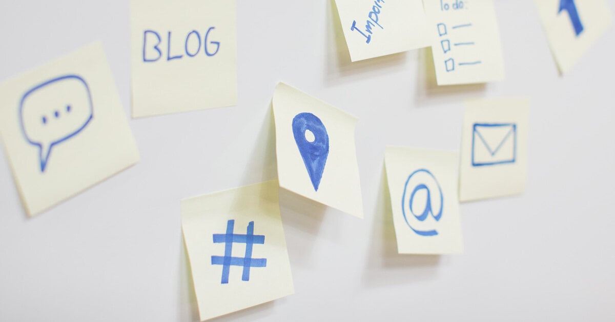 An array of light yellow sticky notes with location and hashtag symbols on them in blue marker.